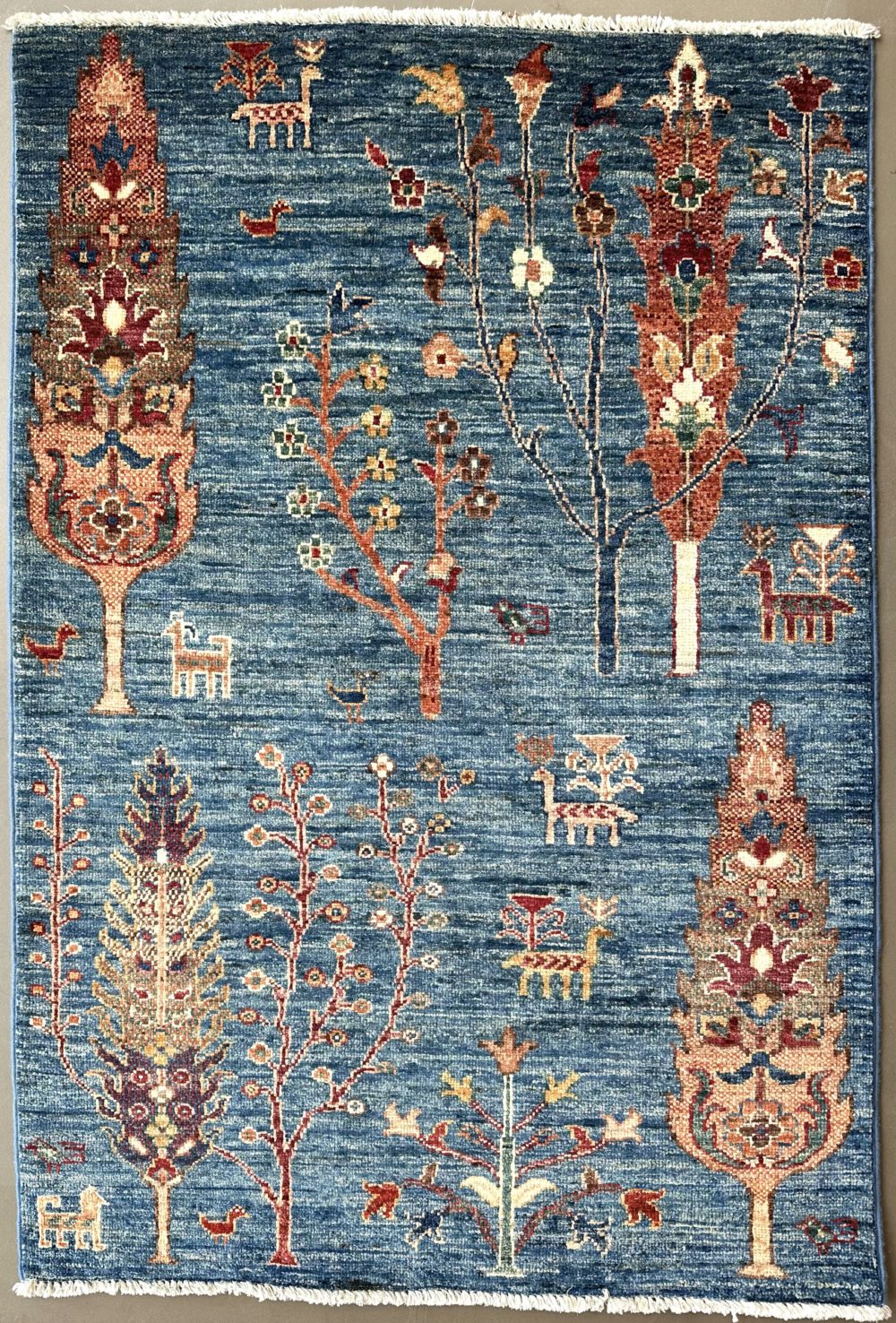 This hand knotted Afghan Khorjeen rug lends a traditional feel to your favorite room. It carries floral design elements along with a pleasing balance of blue, orange and red colors.